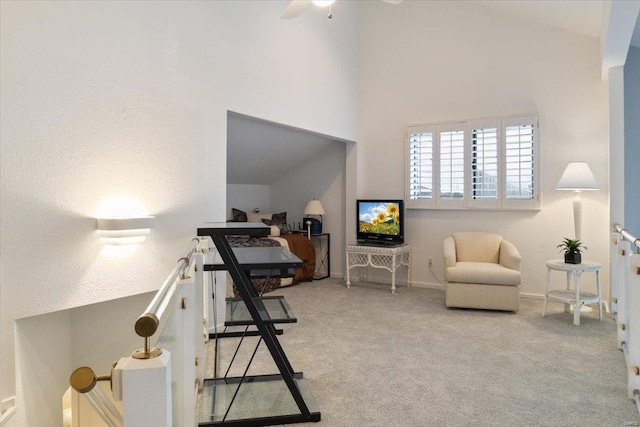 sitting room featuring a towering ceiling, light carpet, and ceiling fan