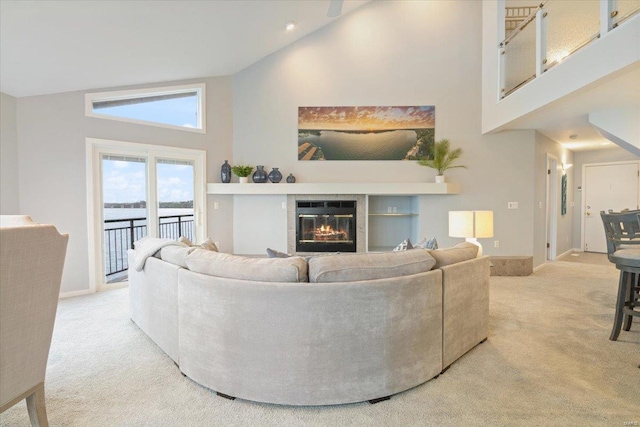 carpeted living room with a water view, a fireplace, and high vaulted ceiling