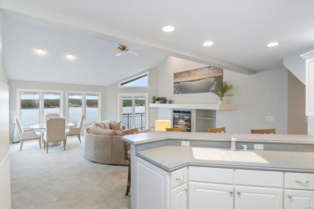 kitchen featuring a water view, sink, light colored carpet, and white cabinets