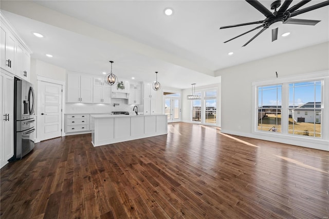 unfurnished living room featuring sink, dark wood-type flooring, and ceiling fan with notable chandelier