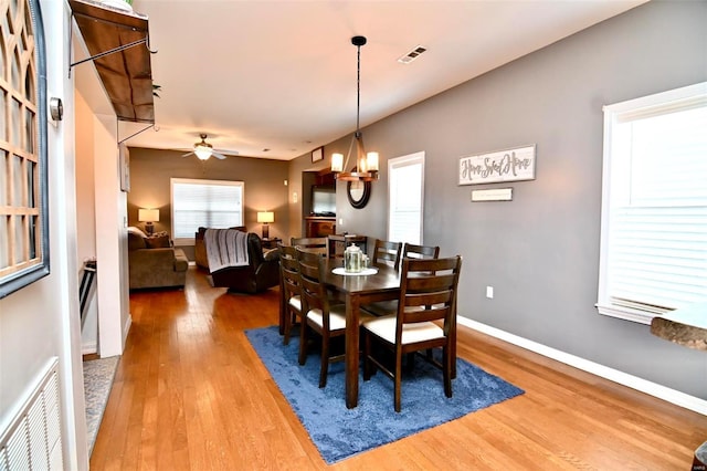 dining area with ceiling fan with notable chandelier and wood-type flooring