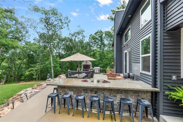 view of patio / terrace featuring a bar and exterior fireplace