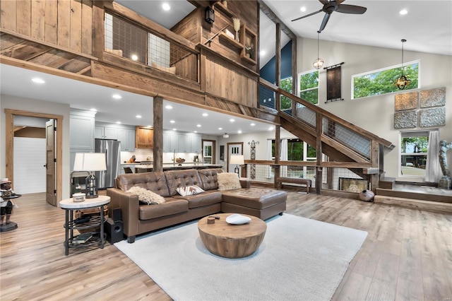 living room featuring ceiling fan, high vaulted ceiling, a healthy amount of sunlight, and light wood-type flooring