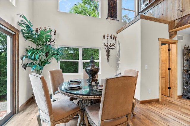 dining room featuring light wood-type flooring and a high ceiling