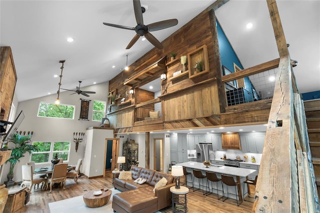 living room featuring sink, high vaulted ceiling, and light hardwood / wood-style floors