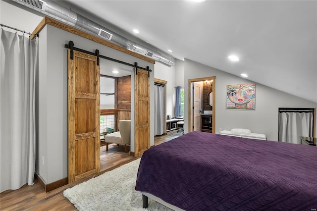 bedroom featuring hardwood / wood-style flooring, lofted ceiling, a barn door, and multiple windows