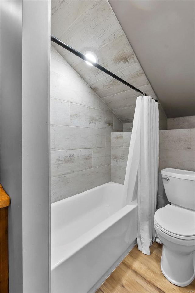 bathroom with lofted ceiling, wood-type flooring, toilet, and shower / bath combo with shower curtain