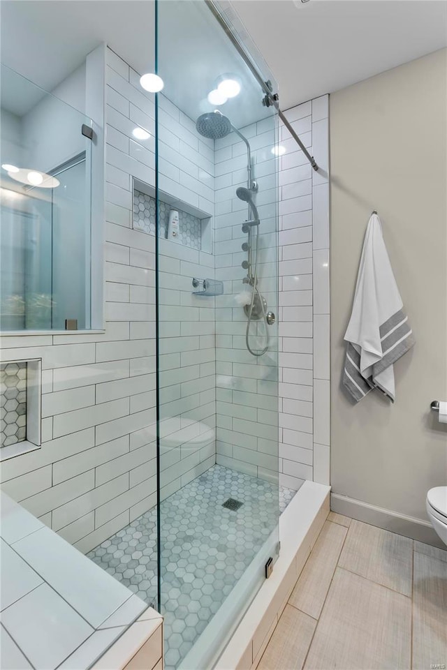 bathroom with a tile shower and toilet