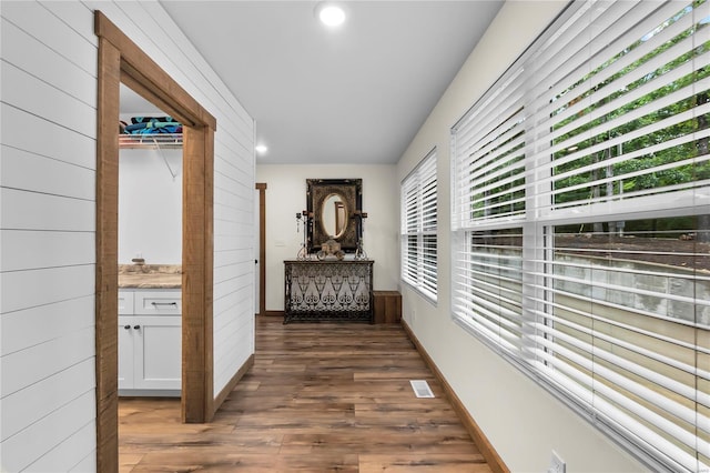 hallway with dark hardwood / wood-style floors and wooden walls