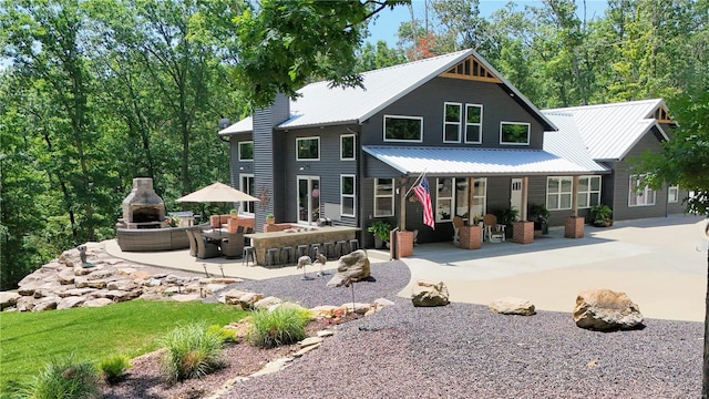 back of house with an outdoor bar, a fireplace, and a patio area