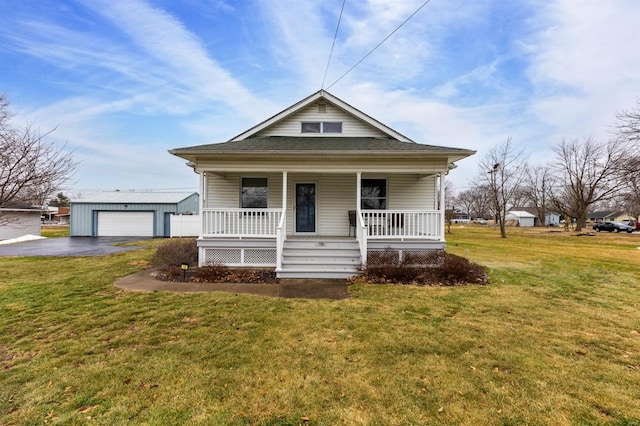 bungalow with a garage, a porch, an outbuilding, and a front lawn