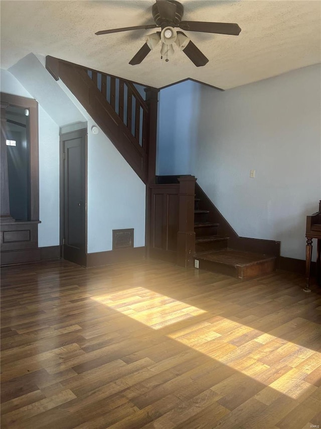 unfurnished living room with ceiling fan, wood-type flooring, and a textured ceiling