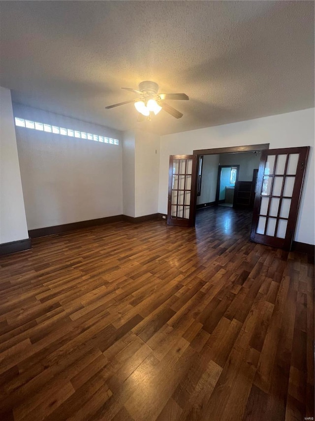 empty room featuring dark wood-type flooring, ceiling fan, a textured ceiling, and french doors