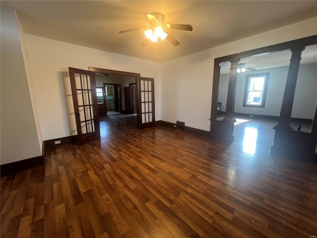 empty room featuring decorative columns, dark hardwood / wood-style floors, ceiling fan, and french doors