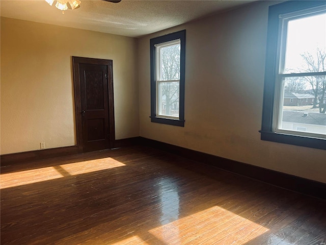 empty room featuring hardwood / wood-style floors, a textured ceiling, and a healthy amount of sunlight