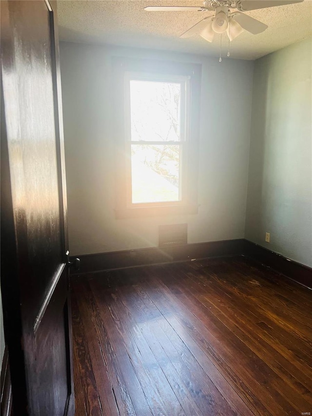 unfurnished room with ceiling fan, dark hardwood / wood-style flooring, and a textured ceiling