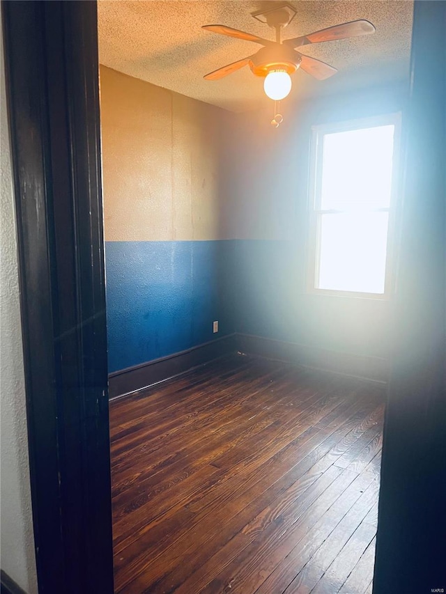 spare room featuring ceiling fan, dark hardwood / wood-style floors, and a textured ceiling