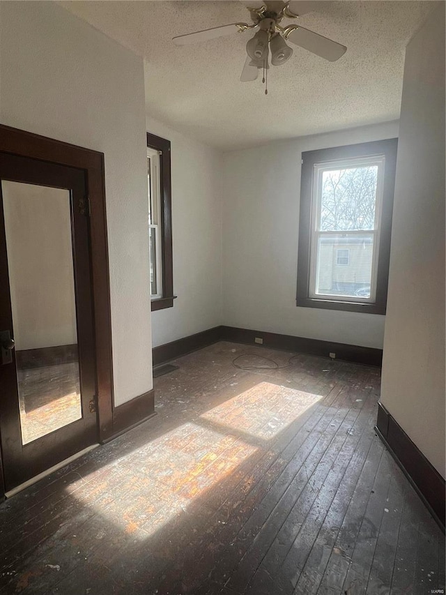 empty room with ceiling fan, dark hardwood / wood-style floors, and a textured ceiling