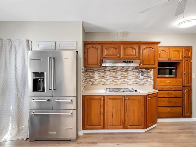 kitchen with tasteful backsplash, light hardwood / wood-style flooring, stainless steel appliances, and ceiling fan