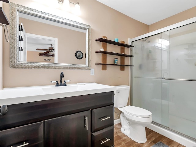 bathroom with wood-type flooring, vanity, an enclosed shower, ceiling fan, and toilet