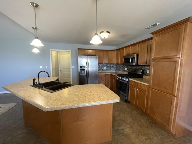 kitchen featuring stainless steel appliances, decorative light fixtures, a kitchen island with sink, and sink