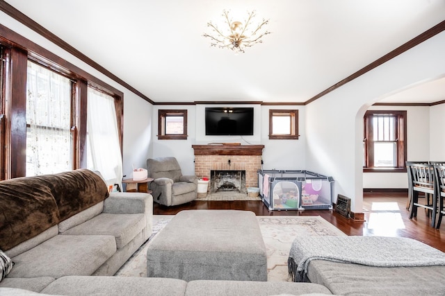 living room with dark wood-type flooring, ornamental molding, and a fireplace