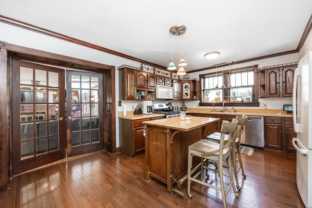 kitchen with appliances with stainless steel finishes, a center island, butcher block countertops, and dark brown cabinets