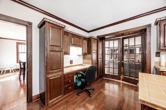 home office featuring built in desk, ornamental molding, dark hardwood / wood-style floors, and french doors