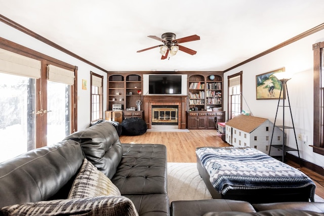 living room with a fireplace, ornamental molding, ceiling fan, and light wood-type flooring