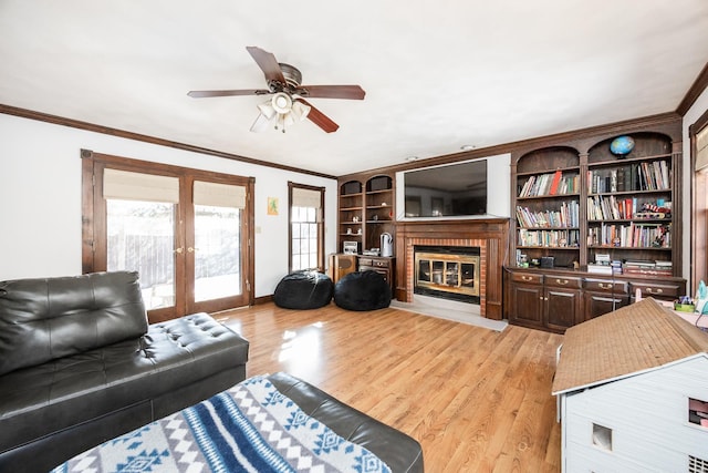 living room with a brick fireplace, light hardwood / wood-style flooring, ornamental molding, and french doors