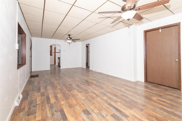 spare room with ceiling fan, dark hardwood / wood-style flooring, and a drop ceiling