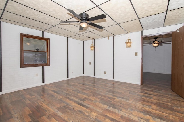 unfurnished room featuring brick wall, dark hardwood / wood-style floors, and ceiling fan