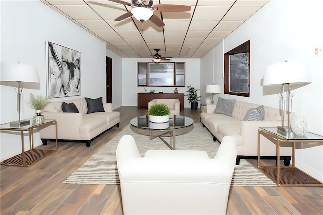 living area with a paneled ceiling, a ceiling fan, and wood finished floors