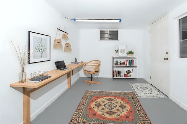 home office featuring concrete flooring and baseboards