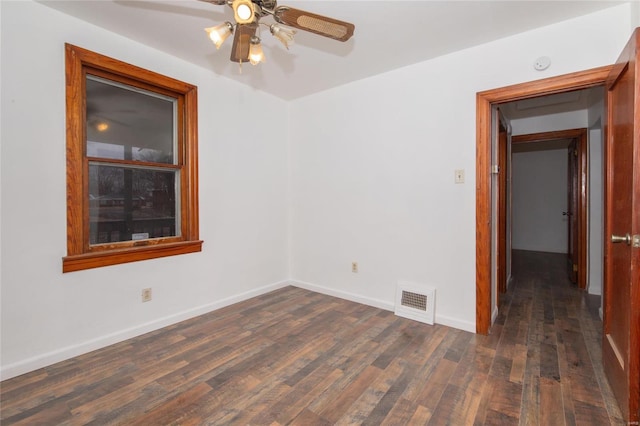 empty room featuring dark wood-style floors, visible vents, baseboards, and a ceiling fan