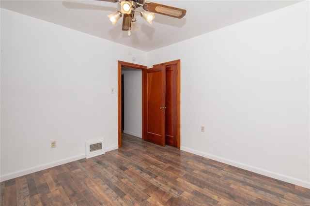 empty room featuring a ceiling fan, dark wood-style flooring, visible vents, and baseboards