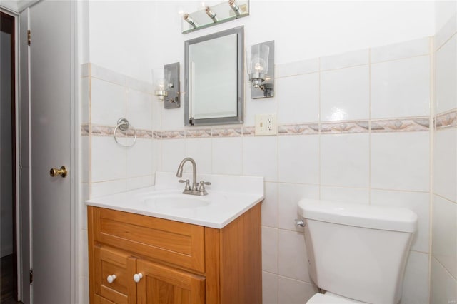 half bath featuring toilet, vanity, and tile walls