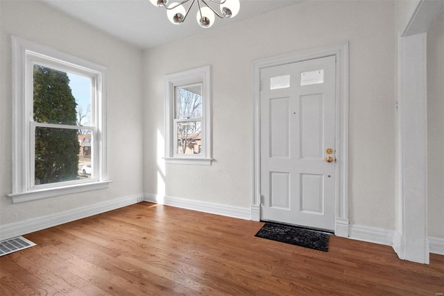 entrance foyer featuring wood-type flooring, a wealth of natural light, and a chandelier