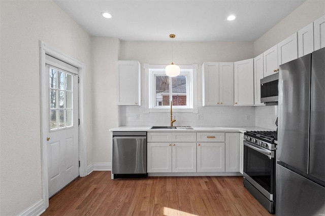 kitchen featuring hanging light fixtures, white cabinetry, appliances with stainless steel finishes, and sink