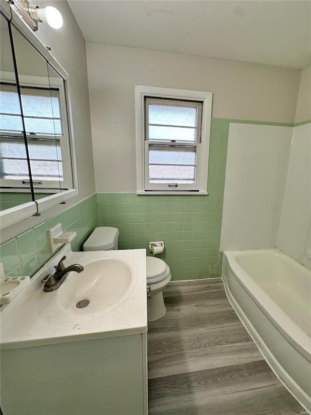 bathroom featuring a healthy amount of sunlight, hardwood / wood-style floors, vanity, and toilet