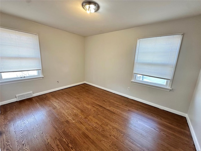 unfurnished room featuring dark wood-type flooring and a healthy amount of sunlight