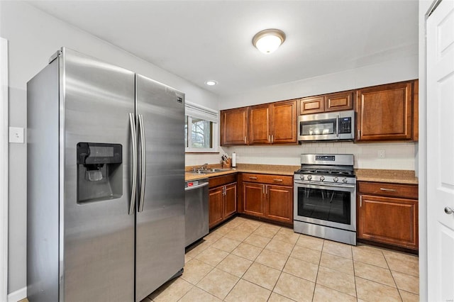 kitchen with tasteful backsplash, appliances with stainless steel finishes, sink, and light tile patterned floors