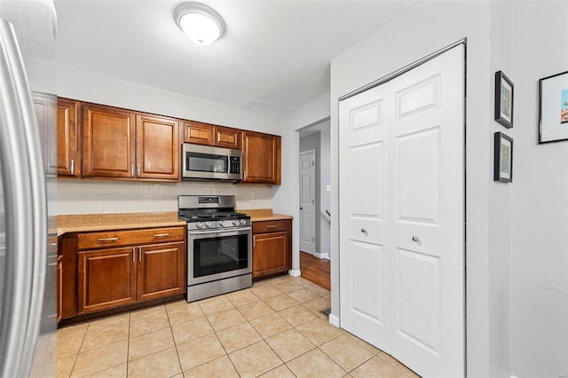 kitchen featuring stainless steel appliances, tasteful backsplash, and light tile patterned flooring