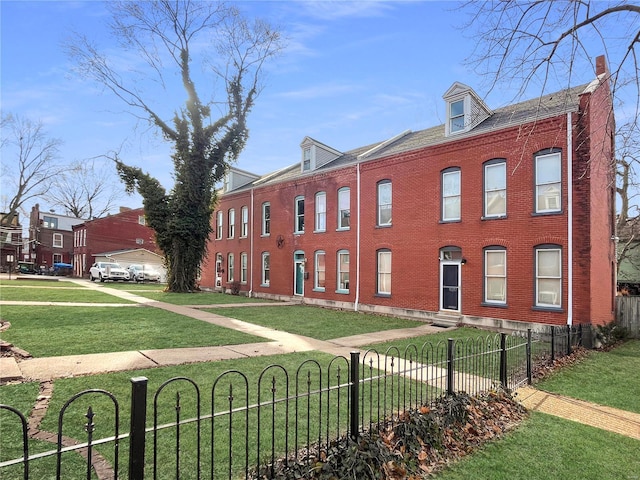 view of front of house with a front yard, brick siding, and a fenced front yard