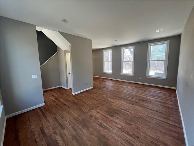 unfurnished living room featuring baseboards and dark wood finished floors