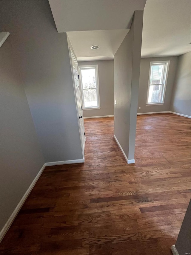 hall with plenty of natural light, wood finished floors, and baseboards