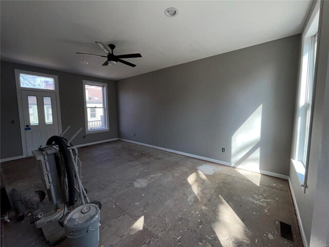 unfurnished living room featuring a ceiling fan and baseboards