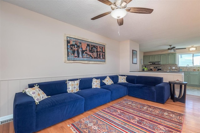 living room with sink, light hardwood / wood-style floors, and a textured ceiling