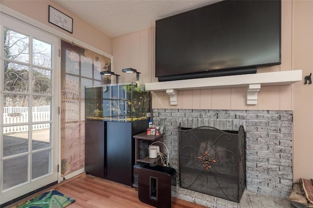 room details with hardwood / wood-style flooring, a brick fireplace, and a textured ceiling