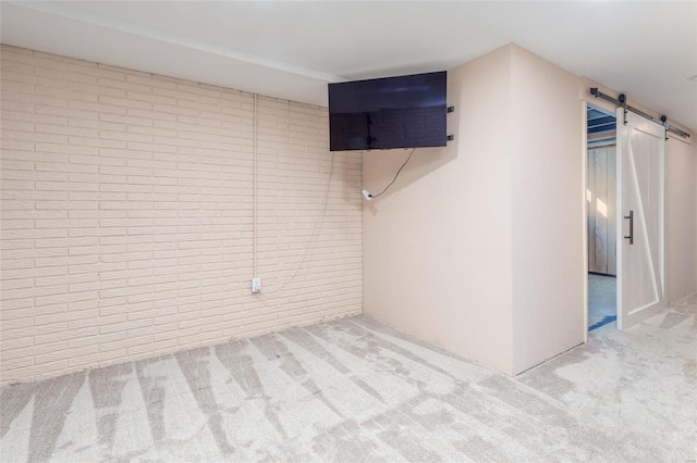 basement featuring a barn door, brick wall, and carpet